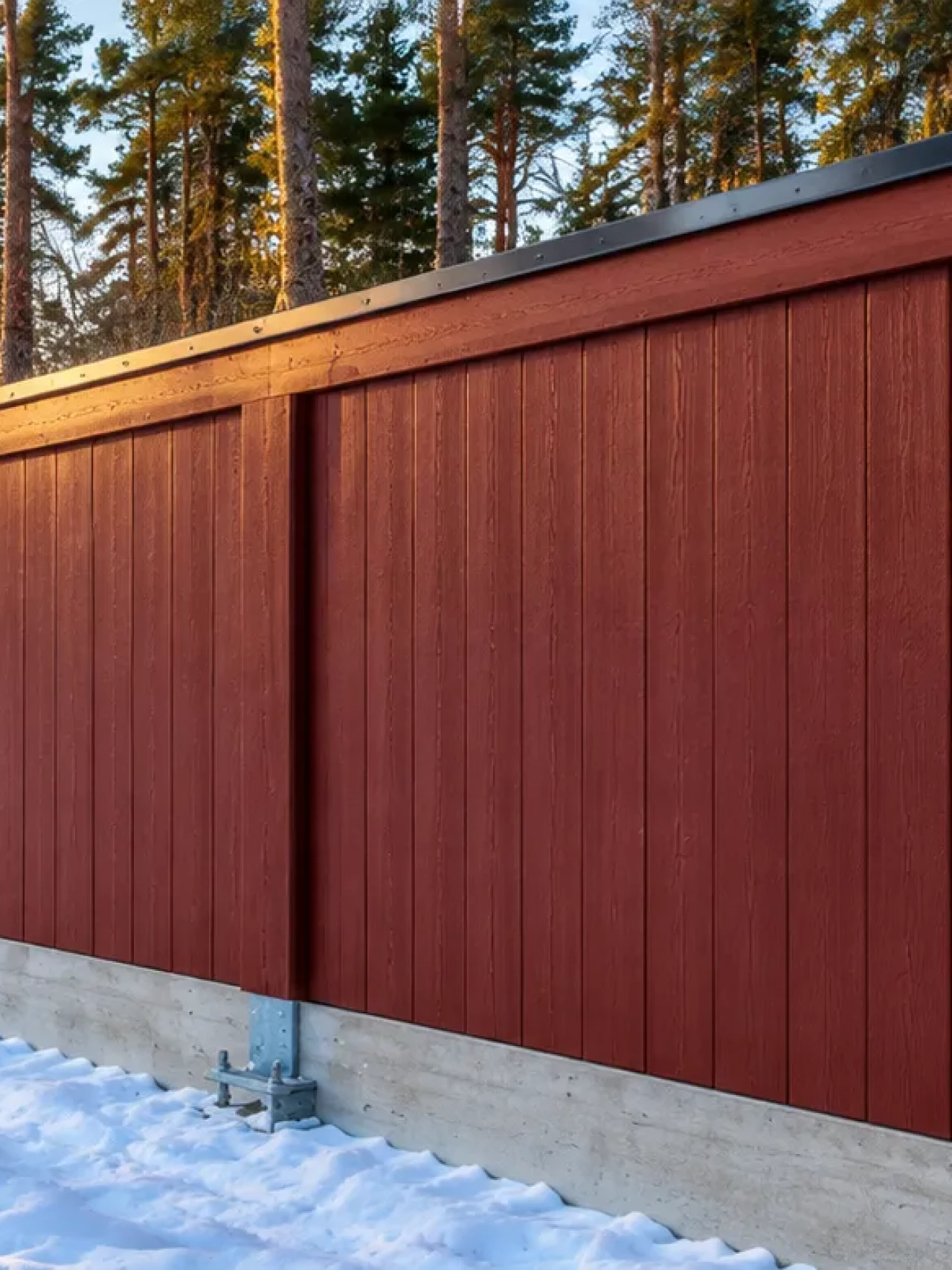 Röd bullerplank i vinterskog vid solnedgång